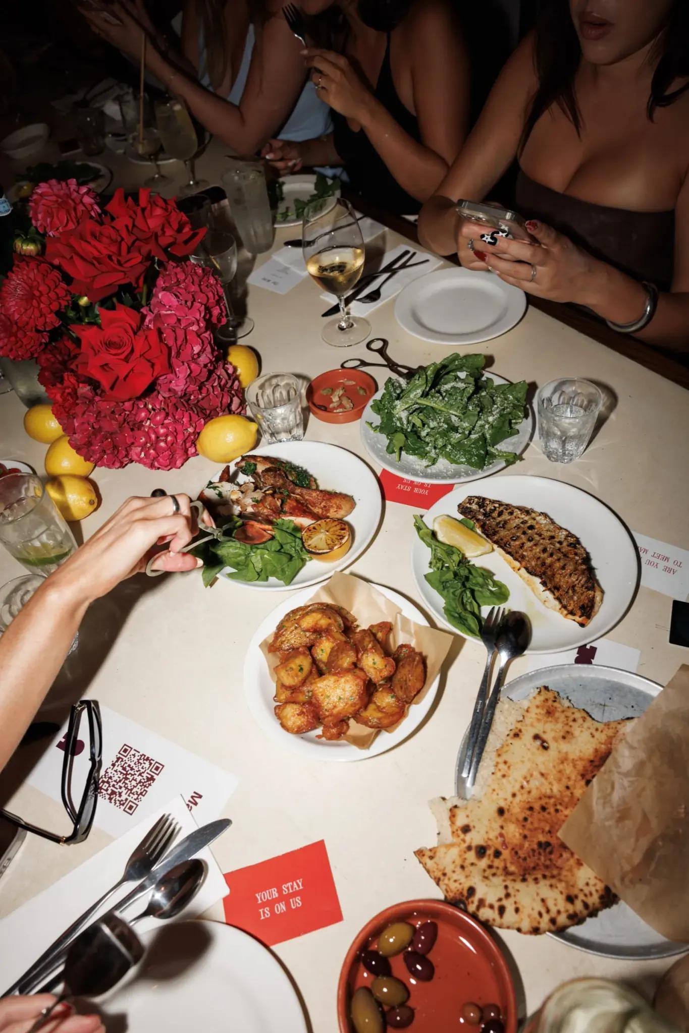 A table of shared plates, flowers and Marlo cards, shot from above